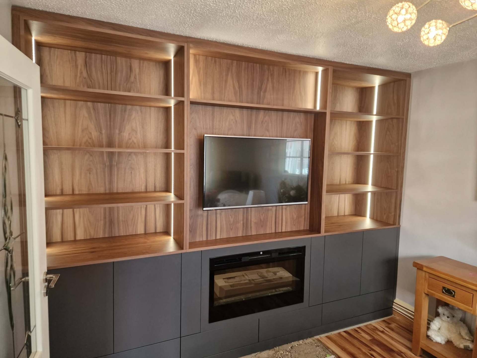 Walnut media wall with hidden storage and warm LED detail.
